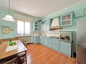 uma grande cozinha com armários azuis e uma mesa e uma mesa sidx sidx em 127 - Appartamento trilocale con doppi servizi, a Numana, in ottima posizione em Numana