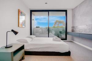 a bedroom with a bed and a large window at Luxurious Elsternwick Apt Living with Parking in Melbourne
