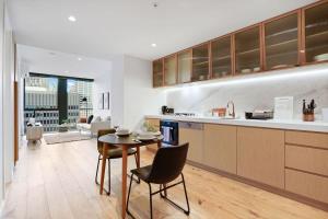 een keuken en een woonkamer met een tafel en stoelen bij Premium CBD Location 19th floor Collins House Apt in Melbourne