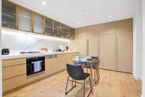 een keuken met een tafel, stoelen en kasten bij Premium CBD Location 19th floor Collins House Apt in Melbourne