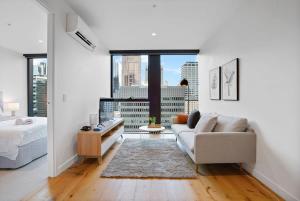 een woonkamer met een bank en een groot raam bij Premium CBD Location 19th floor Collins House Apt in Melbourne