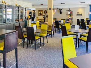 une salle à manger avec des tables et des chaises jaunes dans l'établissement Novotel Saint Avold, à Saint-Avold