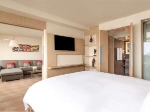 a bedroom with a white bed and a living room at Novotel Abidjan in Abidjan