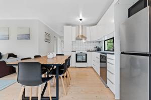 a white kitchen with a wooden table and chairs at Premiere Seaside Home - Relaxing Family Getaway* in Rye