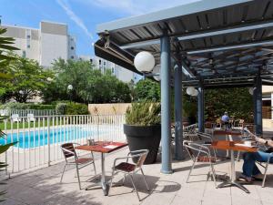 un patio con mesas y sillas junto a una piscina en ibis Marseille Bonneveine Calanques Plages, en Marsella