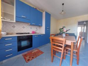 a kitchen with blue cabinets and a table and chairs at Bilocale per l'affitto estivo in Torre Pali +10 photos