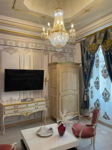 a living room with a television and a chandelier at Suite Présidentielle Maison de L'Église in Narbonne