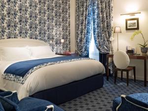 - une chambre dotée d'un lit avec des rideaux bleus et blancs dans l'établissement Hotel Le Royal Lyon - MGallery, à Lyon