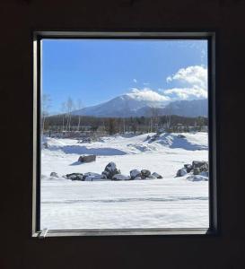 uma janela com vista para um campo coberto de neve com uma montanha em Kita Karuizawa Morino Takibi NO1 em Tsumagoi