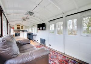 a living room with a couch and a kitchen at The Railway Carriage in Briston
