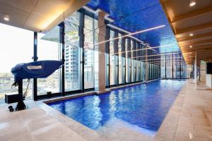 a large swimming pool in a building with windows at Victoria Square - Central Footscray InnerUrban Apt in Melbourne