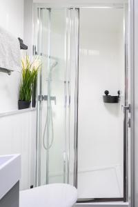 a bathroom with a shower with a toilet and a sink at Tiny Olav houseboat close to the beach and restaurants by Weltevreden Experience in Zeewolde +14 photos