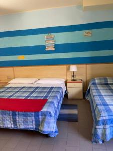 2 letti in una camera con strisce blu e bianche di Hotel Lupo di mare a Marina di Castagneto Carducci