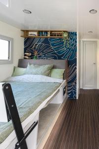 a bedroom with a large bed with a blue wall at Tiny Olav houseboat close to the beach and restaurants by Weltevreden Experience in Zeewolde