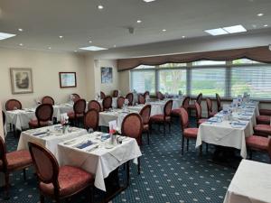 uma sala de jantar com mesas e cadeiras com toalha de mesa branca em Runnymede Court Hotel em Saint Helier