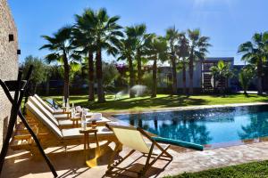 馬拉喀什的住宿－*Villa de luxe à Marrakech, vue sur les montagnes*，游泳池旁设有躺椅和桌子