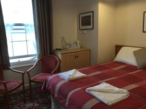 a hotel room with a bed and two chairs and a window at THE TREVONE, Llandudno in Llandudno