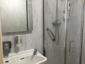 a bathroom with a shower and a sink and a mirror at THE TREVONE, Llandudno in Llandudno