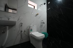 - une salle de bains en noir et blanc pourvue de toilettes et d'un lavabo dans l'établissement Borrbo Beach Hostel Gokarna, à Gokarna