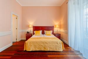 a bedroom with a bed with yellow pillows on it at O Cantinho da Mariazinha in Funchal +31 photos