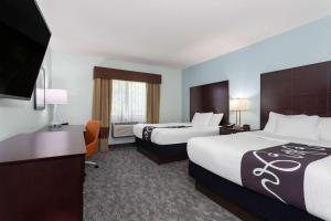 a hotel room with two beds and a flat screen tv at La Quinta by Wyndham Bonita Springs Naples North in Bonita Springs