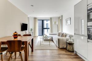 a white living room with a table and a couch at The Wandsworth Luxury Apartment in London