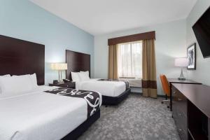 a hotel room with two beds and a desk at La Quinta by Wyndham Bonita Springs Naples North in Bonita Springs