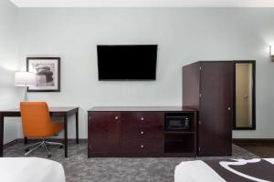 a hotel room with a desk and a television on a wall at La Quinta by Wyndham Bonita Springs Naples North in Bonita Springs