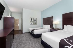 a hotel room with two beds and a desk at La Quinta by Wyndham Bonita Springs Naples North in Bonita Springs