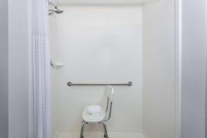 a white toilet in a bathroom with a chair at La Quinta by Wyndham Bonita Springs Naples North in Bonita Springs