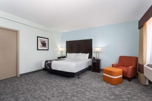 a hotel room with a bed and a chair at La Quinta by Wyndham Bonita Springs Naples North in Bonita Springs