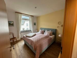 una camera da letto con un letto con lenzuola rosa e una finestra di NEU - Ferienwohnungen im Winzergarten a Traben-Trarbach