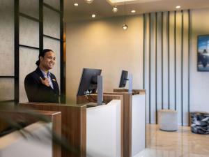 un homme assis à un bureau avec un ordinateur dans l'établissement The Sebel Auckland Manukau, à Auckland