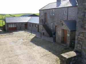 an old stone building with a courtyard in front of it at Knotts Farm Holiday Cottages in Lancaster