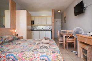 1 dormitorio con cama, mesa y cocina en Azahara Playa 2 - Studio, en Los Cristianos