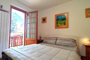 a bedroom with a bed and a large window at Casa Vacanza Presolana con giardino e box auto in Castione della Presolana