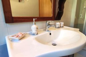La salle de bains est pourvue d'un lavabo blanc et d'un miroir. dans l'établissement Casa Vacanza Presolana con giardino e box auto, à Castione della Presolana