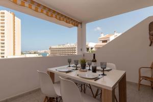 a table with chairs and wine bottles on a balcony at Paloma Beach 10 - One Bed with sea view and wifi internet in Los Cristianos