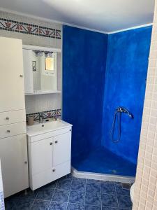 ein blaues Bad mit einem Waschbecken und einer Dusche in der Unterkunft Heras house in Ireo