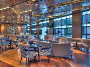 a restaurant with tables and chairs and windows at Movenpick Hotel & Convention Centre KLIA in Sepang