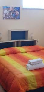 un letto colorato con due asciugamani bianchi di Borgo San Giorgio Apartment a Castelmola
