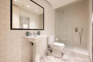a bathroom with a toilet and a sink and a mirror at Central Soho Loft with A C & Concierge in London