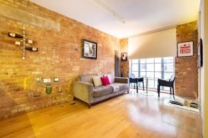 a living room with a couch and a brick wall at Central Soho Loft with A C & Concierge in London