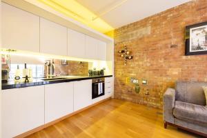 a kitchen with white cabinets and a brick wall at Central Soho Loft with A C & Concierge in London