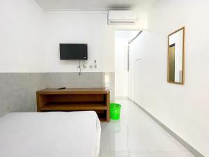 a bedroom with a bed and a tv on a wall at RedDoorz at Kedawung Cirebon 