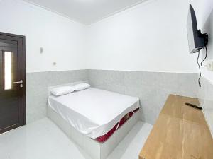 a white room with a bed and a tv at RedDoorz at Kedawung Cirebon 