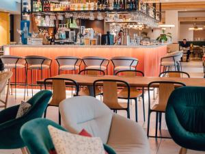 un restaurant avec des tables et des chaises ainsi qu'un bar dans l'établissement Mercure Avignon Gare TGV, à Avignon