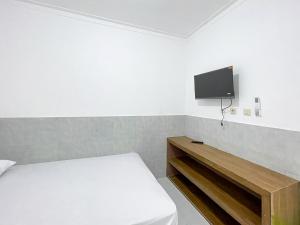 a bedroom with a bed and a tv on the wall at RedDoorz at Kedawung Cirebon 