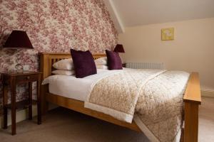 sypialnia z łóżkiem z fioletowymi poduszkami w obiekcie Dairy Cottage w mieście Knapton