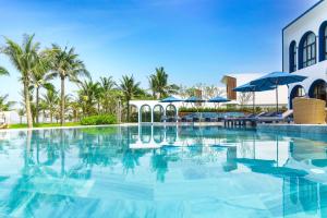 una piscina en un complejo con palmeras en Wyndham Hoi An Royal Beachfront Resort & Villas en Hoi An